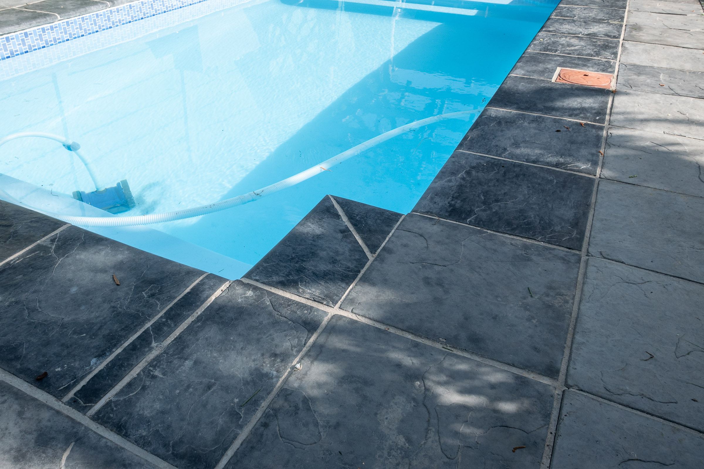 horizon-paving-van-zyl-terraces-panorama-02 Paving around swimming pool with charcoal paving slabs and cobble border at Panorama residence