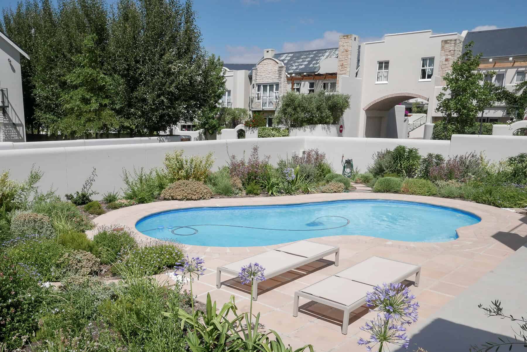 horizon-paving-curved-pool-patio-paving Curved paving around kidney-shaped swimming pool using paving slabs and cobbles in natural sandstone colour